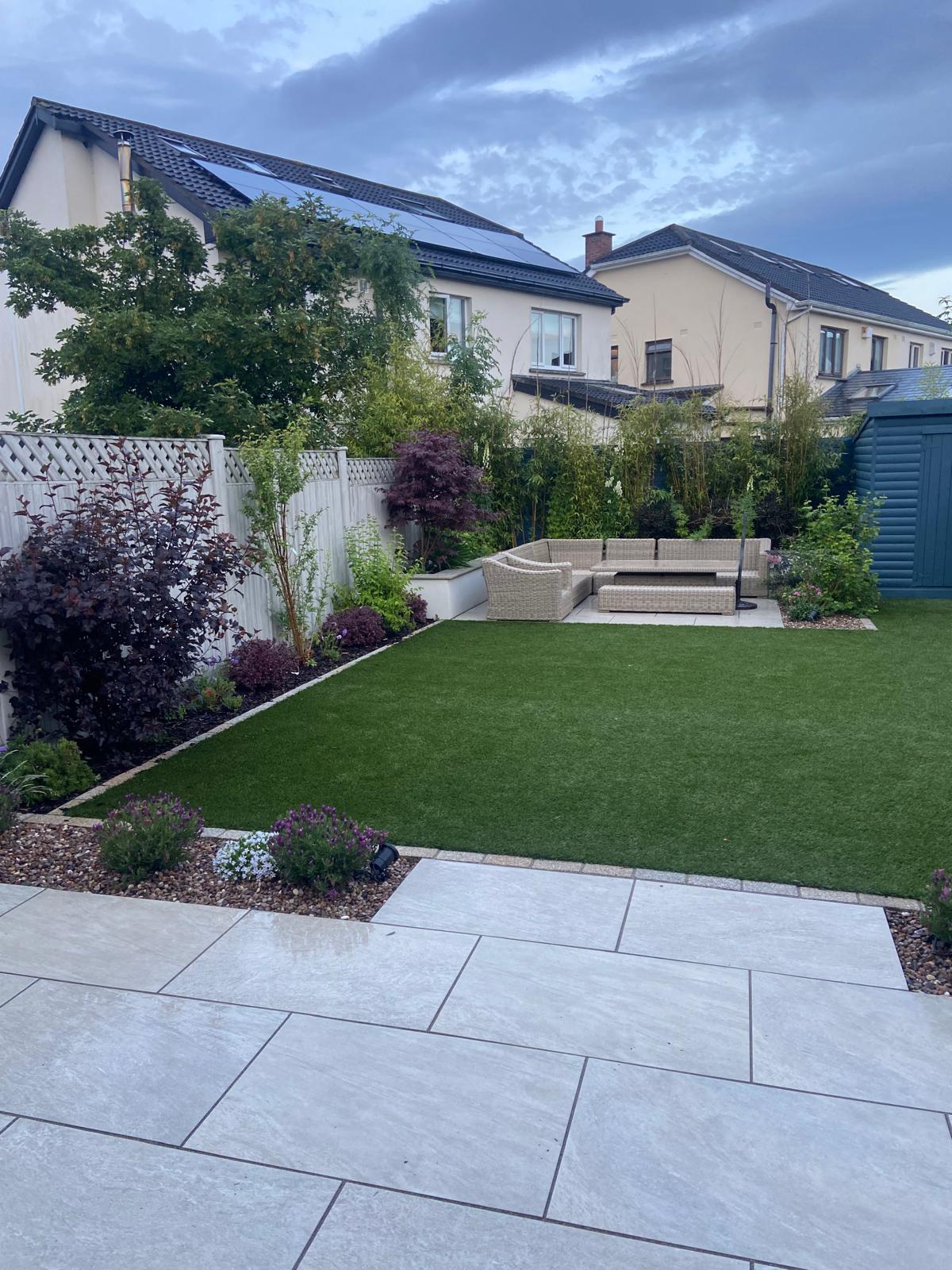 Artificial grass garden with landscaped borders and paved seating area